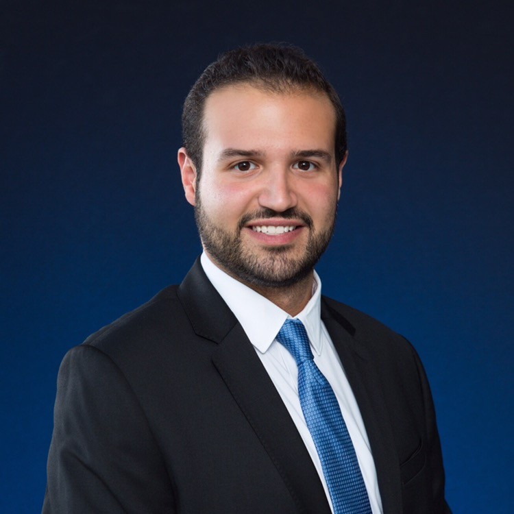 a man wearing a suit and tie smiling at the camera